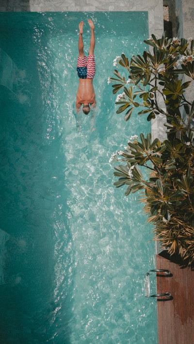 男子向游泳池跳水的高角度摄影